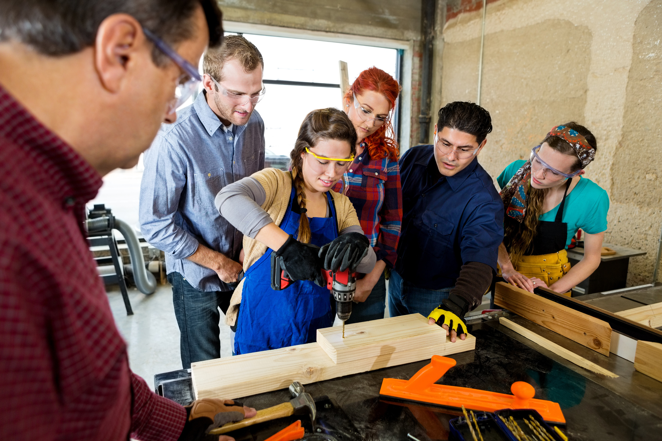 Woman drills hole in board in makerspace